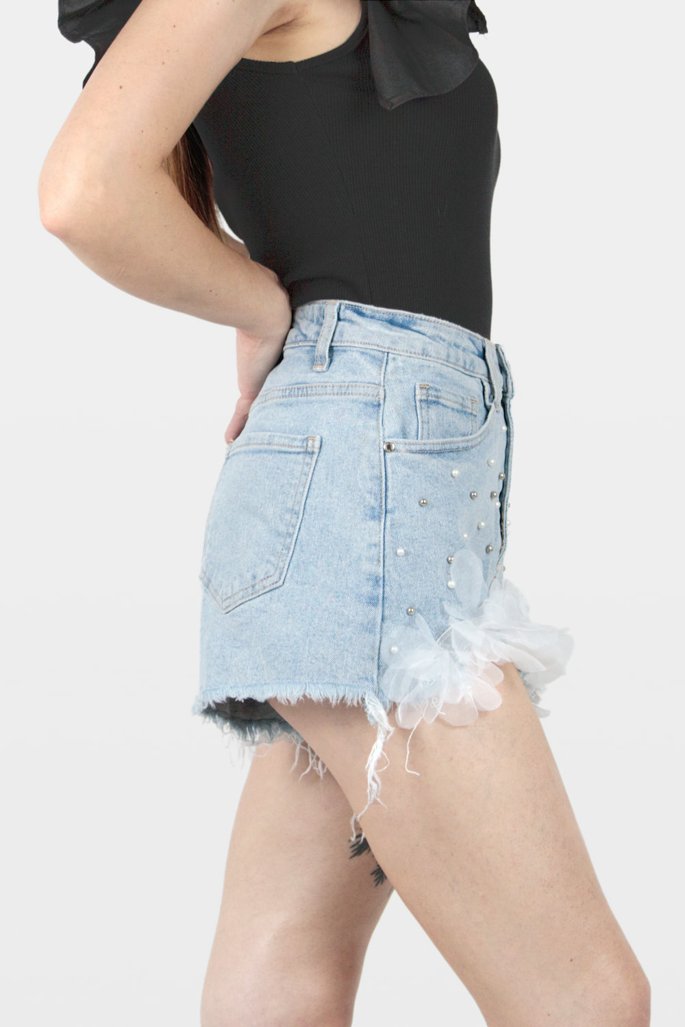 Calções de ganga com detalhe de flores e pérolas de fantasia azul, lado.